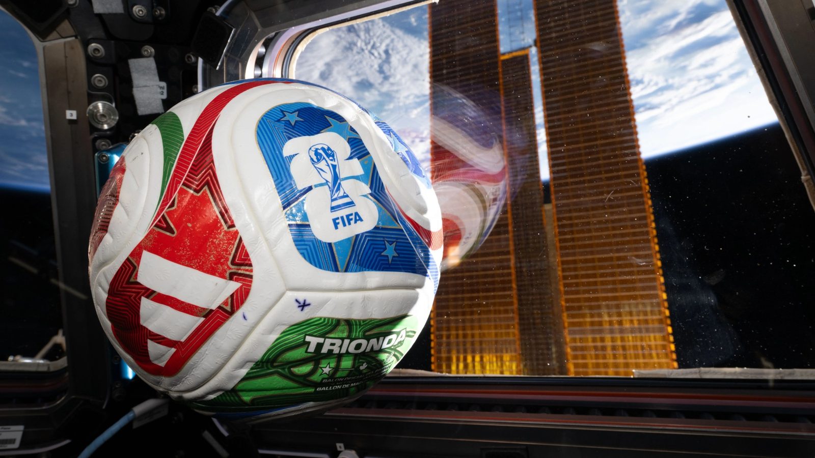 Футбольный мяч с надписью "fifa 26" лежит у иллюминатора, через который из космоса видна Земля